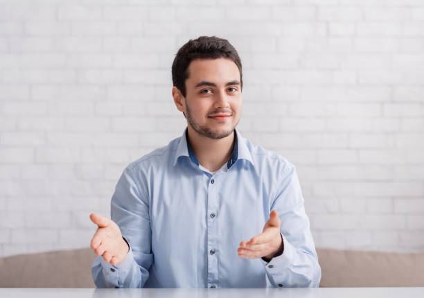 istock Friendly man point hands to empty space, sitting on couch in interior 1250209011