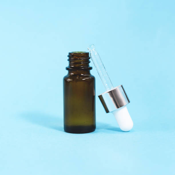 istock A cosmetic jar with glass dropper on the blue background. 1250210244