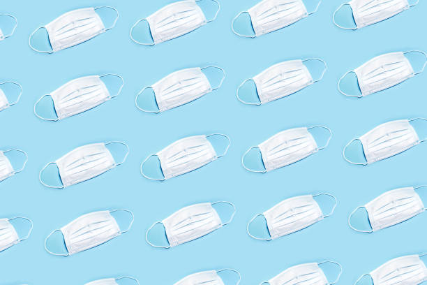 istock Pattern from white medical mask on the blue background. 1250211031