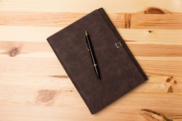 istock Leather-bound business notebook with a pen on wooden background. 1250214034