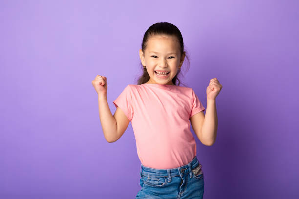 petite fille asiatique heureuse secouant des poings, faisant le geste gagnant - child celebration cheering victory photos et images de collection