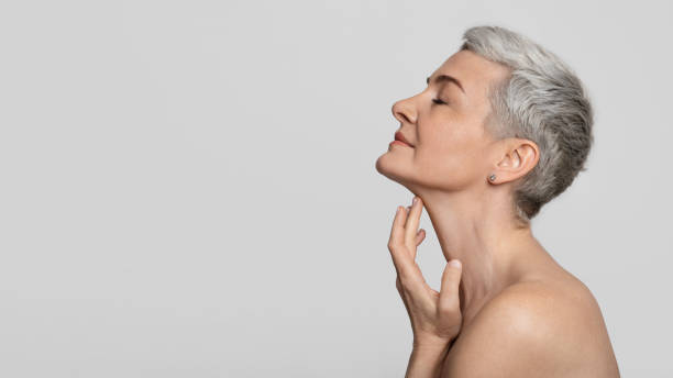 anti-age-behandlung. schöne frau mittleren alters, die weiche haut am hals berührt - hands in head stock-fotos und bilder