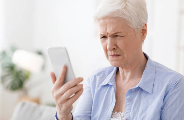 myopia concept. elderly woman squinting while looking at smartphone screen - eyesight vision imagens e fotografias de stock