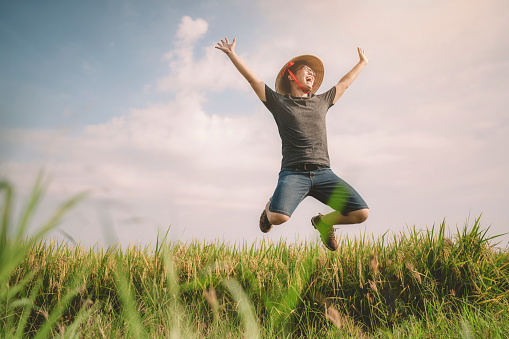 a farmer jumping mid air happily laughing at sekinchan agriculture field