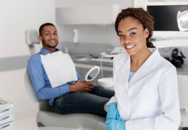 istock Smiling dentist and patient looking at camera, dental cabinet interior 1250218897