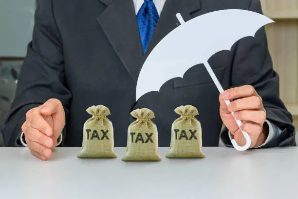 Photo of Taxpayer uses a hand and umbrella to protect tax bags