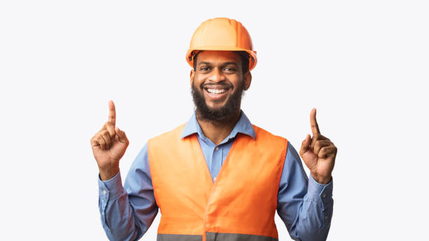 istock Cheerful Construction Worker Pointing Fingers Up On White Studio Background 1250221441