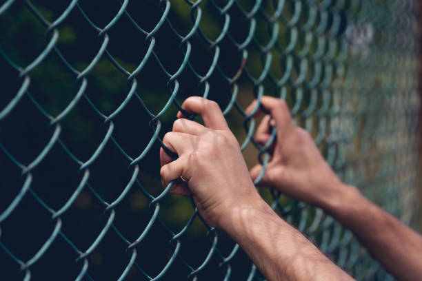 joven mano sosteniendo en la valla de eslabones de cadena para la libertad, día de los derechos humanos, concepto de inmigrante. - just kids fotografías e imágenes de stock