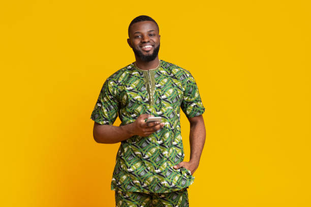 istock Smiling black guy in african costume using mobile phone 1250222585