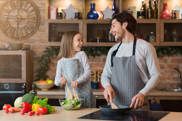 istock Happy father and daughter having fun while cooking lunch together in kitchen 1250223027