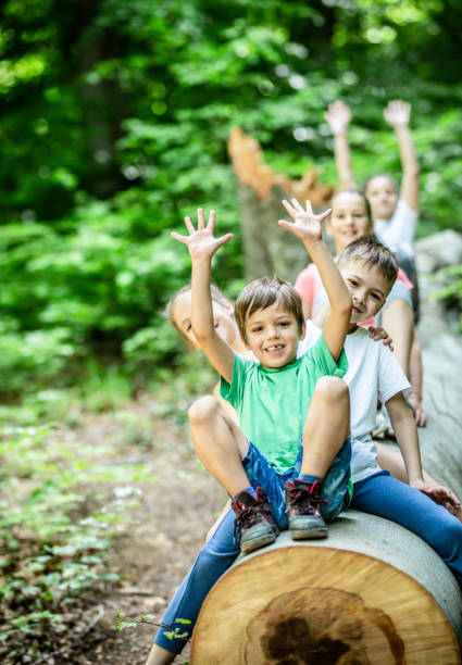 Group of children playing and sitting on tree in the woods Stock photo stock photo