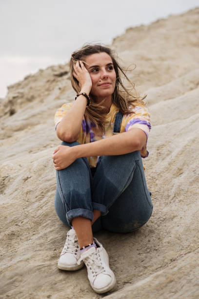 istock Young woman sitting on rocks 1250224885