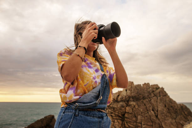 istock Young woman using a DSLR camera in a beautiful coast area 1250225543