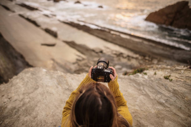 istock Young woman using a DSLR camera in a beautiful coast area 1250225662