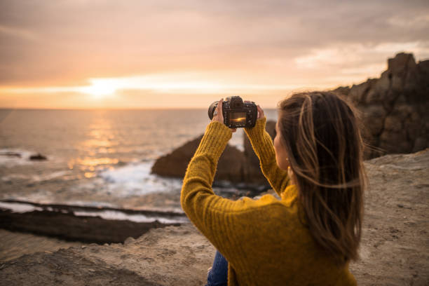 istock Young woman using a DSLR camera in a beautiful coast area 1250225683