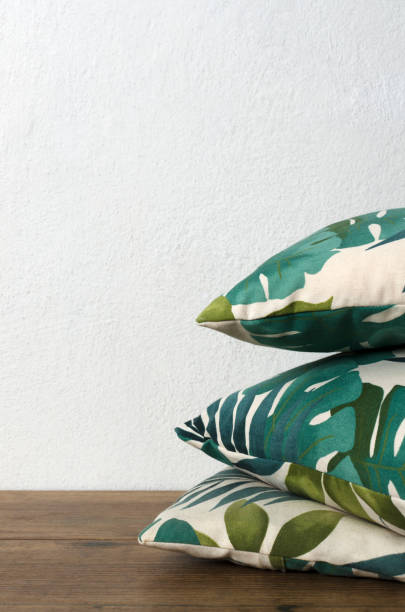 istock Vertical image.Stack of pillows with floral ornament on the brown floor against white wall.Empty space 1250226243
