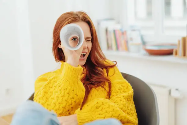 happy redhead woman looking through paper telescope