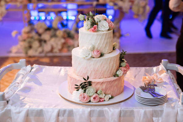 istock Big white wedding cake with pink roses on table 1250229243