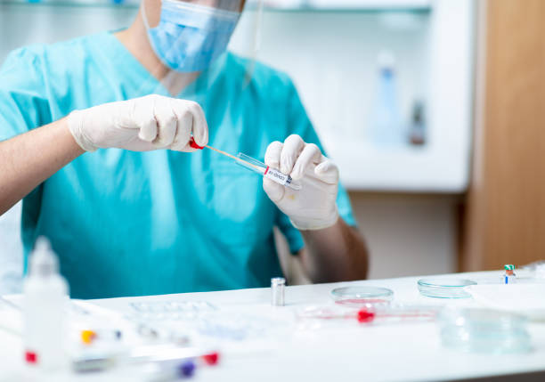 istock Lab technician taking saliva from COVID-19 test kit for analysis 1250233425