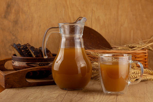 homemade bread kvass. summer carbonated soft drink. glass and carafe on a wooden table. black overseas rye bread - ingredients for a drink. copy space. traditional cold rye drink kvas in a jug - rustic beer brewery indoors imagens e fotografias de stock