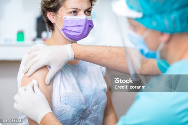 Female Patients Arm Disinfected With Cotton Pad For Vaccination Stock Photo - Download Image Now