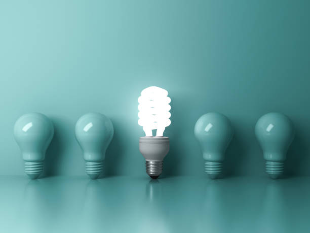 istock One glowing compact fluorescent lightbulb standing out from unlit incandescent bulbs on green background 1250236975
