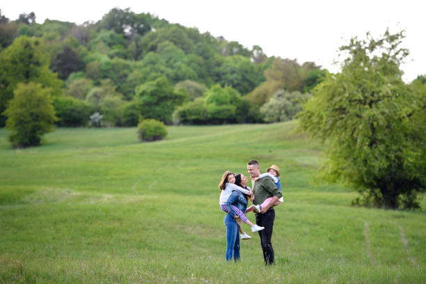 Happy family with two small daughters standing outdoors in spring nature.