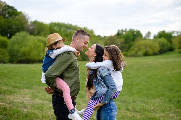 istock Happy family with two small daughters standing outdoors in spring nature. 1250237860