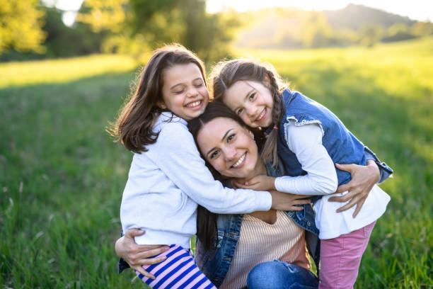 istock Mother with two small daughters having fun outdoors in spring nature, hugging. 1250237919