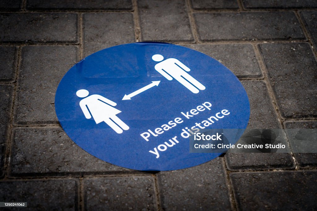 Covid-19 social distancing notice disk on ground Blue disk notice on the ground says " please keep your distance " Coronavirus Stock Photo
