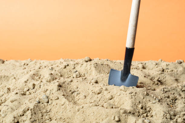 istock shovel stuck in the sand on an orange background 1250242074