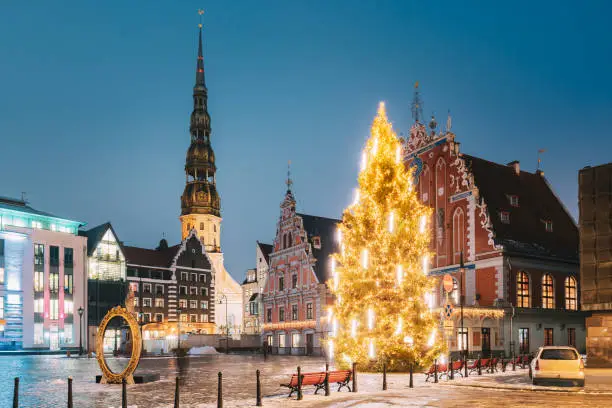 Photo of Riga, Latvia. Town Hall Square, Popular Place With Famous Landmarks On It In Bright Evening Illumination In Winter Twilight. Winter New Year Christmas Holiday Season