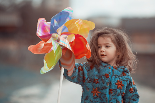 Baby girl holding pinwheel observing and feeling playful outdoors