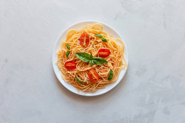istock Pasta with cherry tomatoes, cheese and basil on a light background. Top view, copy space 1250242725