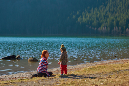 Redhead mother and baby daughter at the lake,  feeling happy while playing