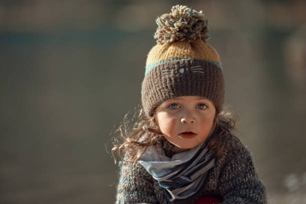 Beautiful baby girl with rosy cheeks Little baby girl at the lake with rosy cheeks, curly hair and pullover looking at the camera rosy cheeks stock pictures, royalty-free photos & images