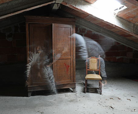 spooky ambiance of an attic of a haunted house with a wardrobe and chair and a moving presence