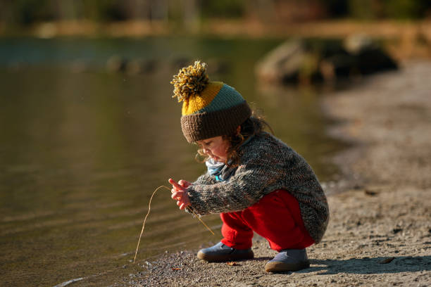 Little baby girl at the lake, playing on the edge of water, touching