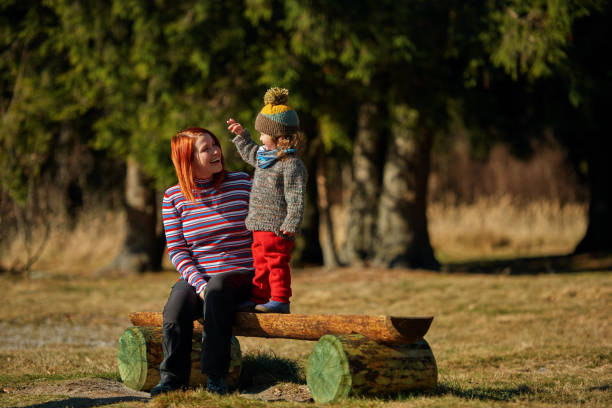Redhead mother and baby daughter in the forest, exploring nature, feeling happy, smiling and laughing