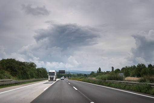 Wiesbaden, Germany - June 16, 2020: Dense traffic and road users on German highway A3 between Niedernhausen and Wiesbadener Kreuz on a cloudy day. A3 is a heavily frequented German highway that connects Passau in the Southeast with the Dutch border in Germany. Rear view camera photography