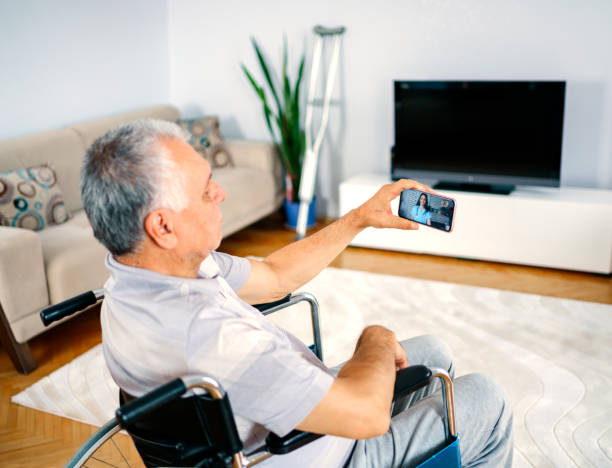 istock older man sitting in wheelchair, using mobile phone 1250244872