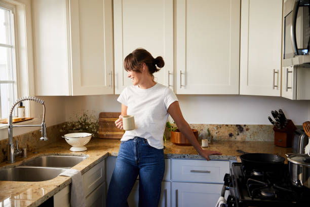istock Young woman drinking coffee in her kitchen and smiling 1250248328