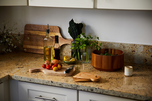 Variety of healthy vegetables being prepared for a salad sitting on a marble counter in a kitchen