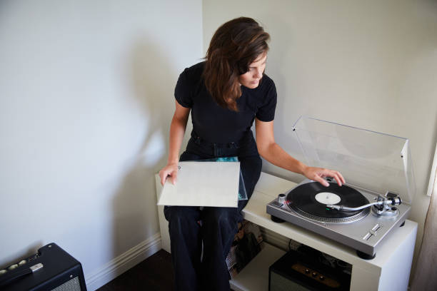 istock Young woman playing records on a turntable at home 1250249872