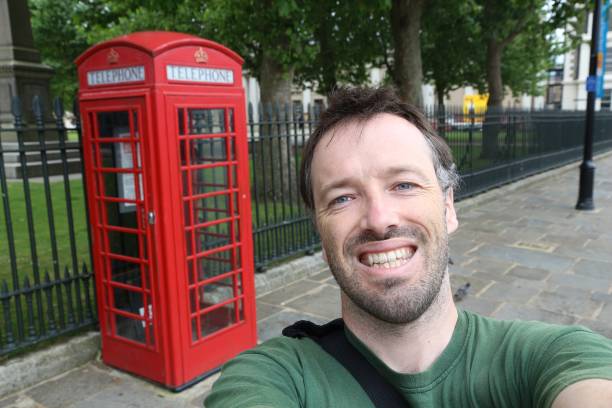 Tourist selfie with London phone booth - red telephone in the UK.