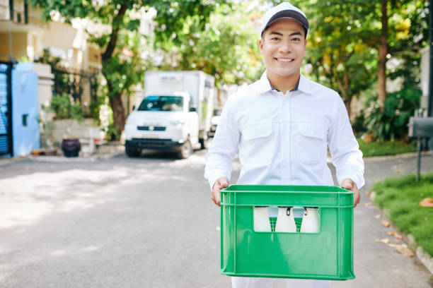 joyful delivery man with milk - milkman fotografías e imágenes de stock