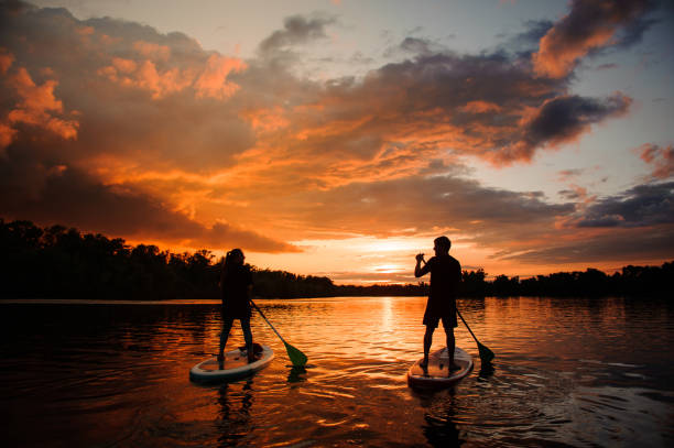 istock rear view of two people on sup boards which floating on the river at sunset 1250251621