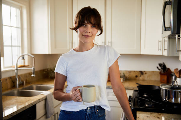 istock Young woman drinking coffee in her kitchen and smiling 1250251953