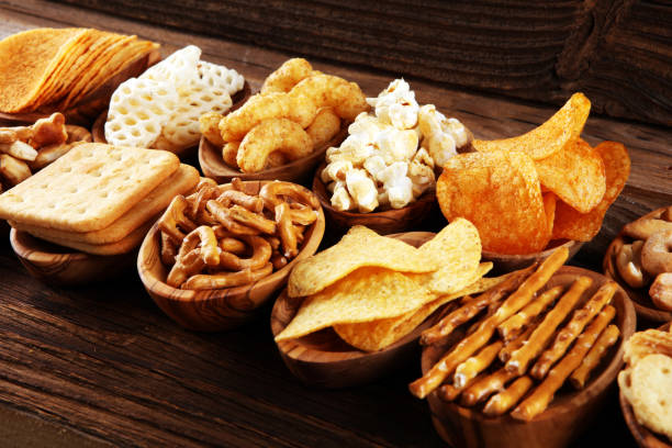 istock Salty snacks. Pretzels, chips, crackers in wooden bowls on table 1250258312