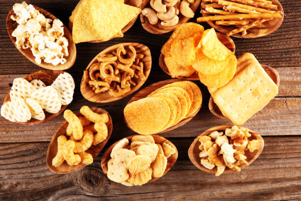 istock Salty snacks. Pretzels, chips, crackers in wooden bowls on table 1250258402